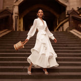 Woman in a white dress standing on stone steps with a rustic background