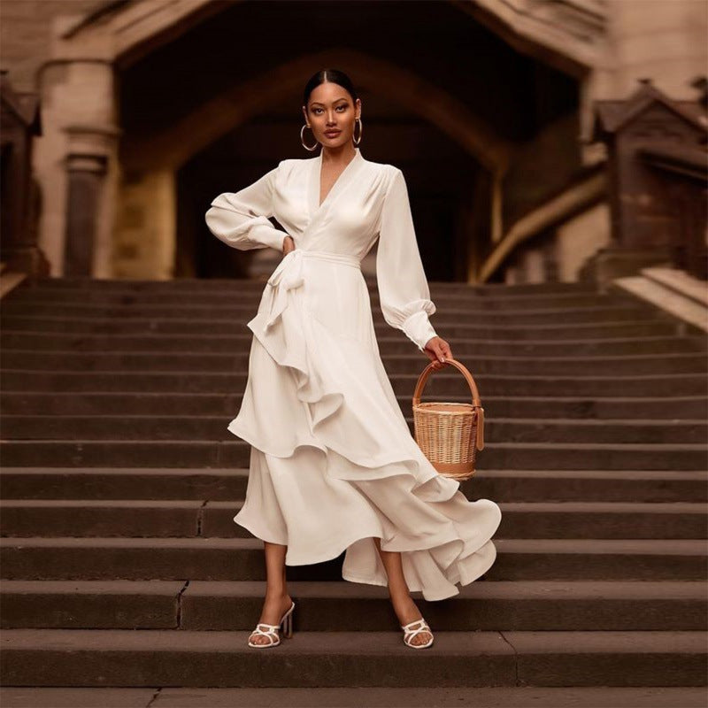 Woman in a white dress standing on stone steps holding a woven basket.