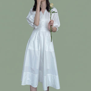 White V-neck puff sleeve dress styled with brown sandals and a straw tote bag